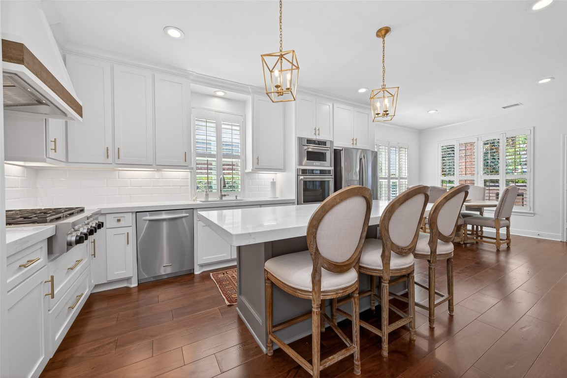 18207 Yukon Ridge Trail Humble, TX 77346 - Photo 10 of 49 This spacious kitchen features modern white cabinetry, a large island with seating, stainless steel appliances, and elegant pendant lighting. Ample natural lighting.