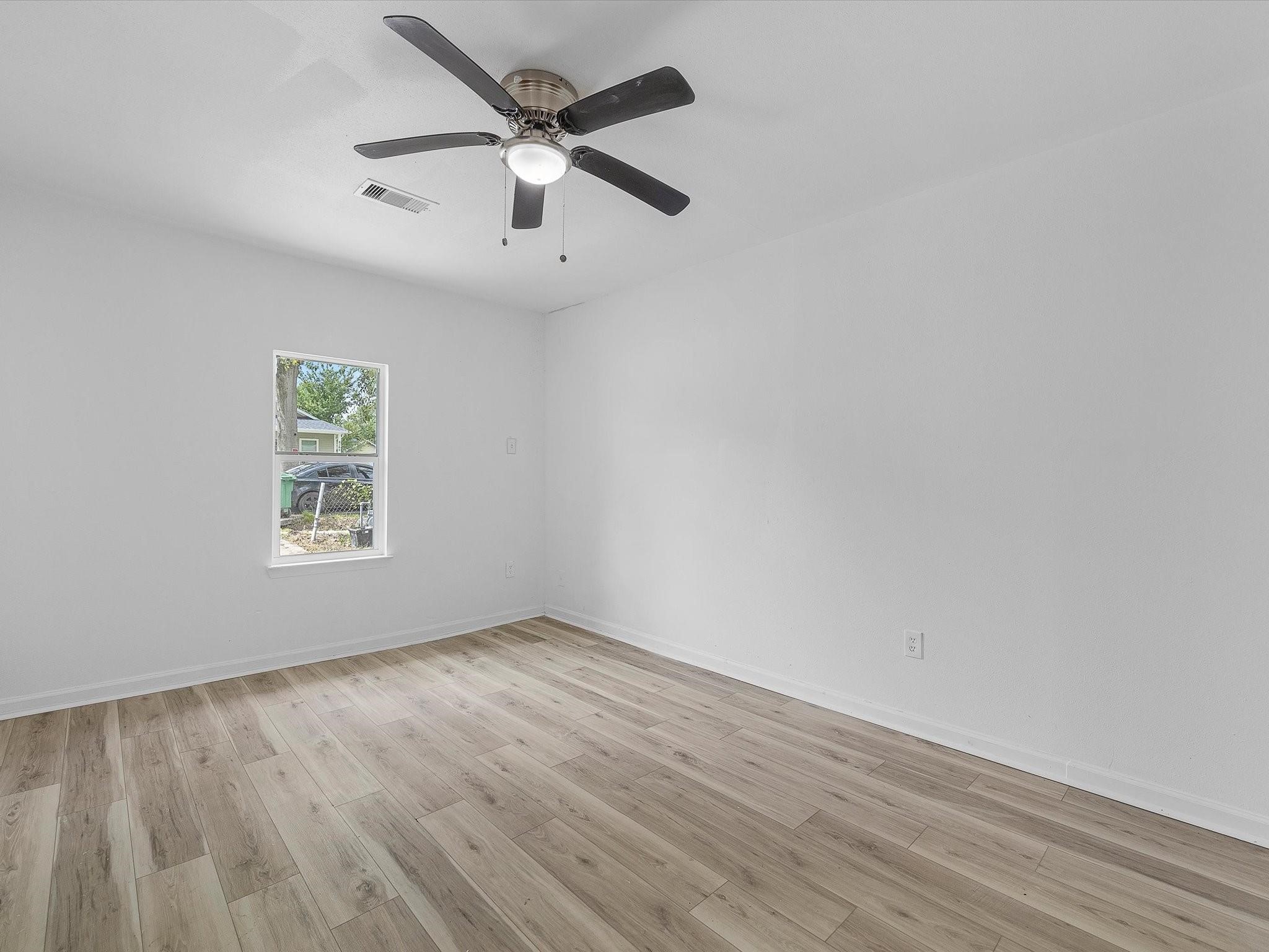 8161 Record Street Houston, TX 77028 - Photo 4 of 12 an empty room with wooden floor ceiling fan and windows