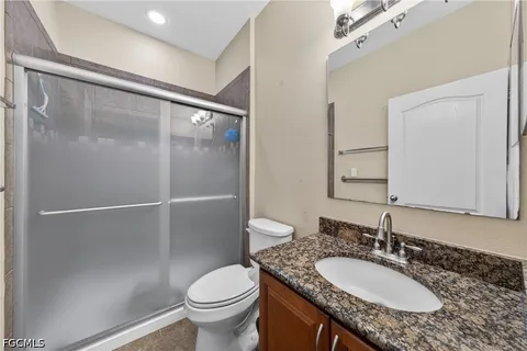 a bathroom with a granite countertop sink toilet and a mirror