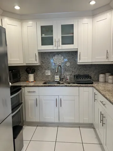 a kitchen with granite countertop white cabinets and stainless steel appliances