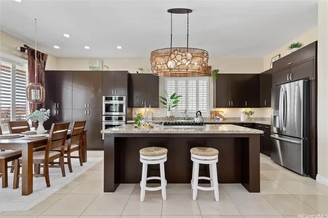 a kitchen with stainless steel appliances granite countertop a table chairs and a refrigerator
