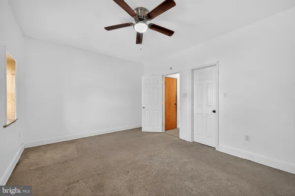 an empty room with a window and a fan