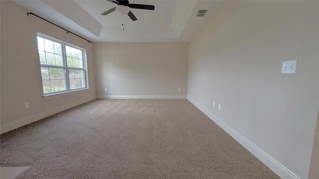 an empty room with a ceiling fan and window