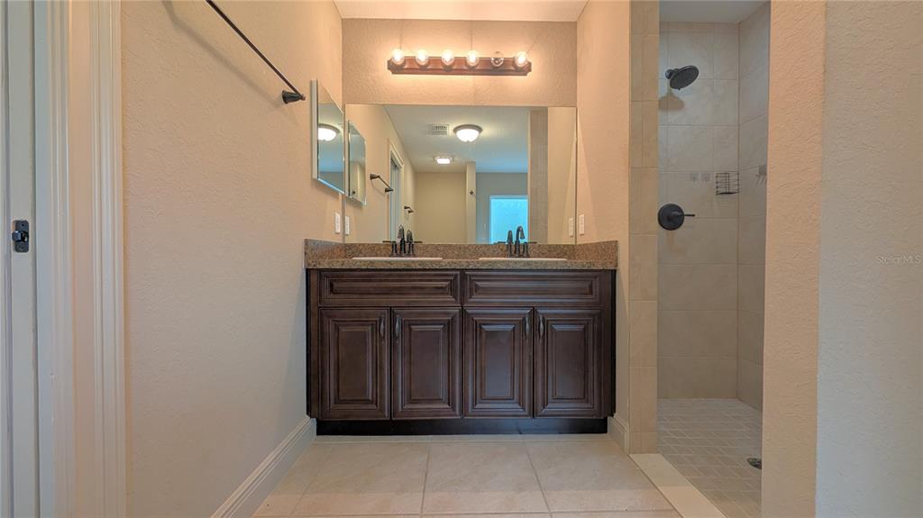 8802 Southwest 135th Place Ocala, FL 34473 - Photo 36 of 39 a bathroom with a granite countertop sink a mirror and a vanity