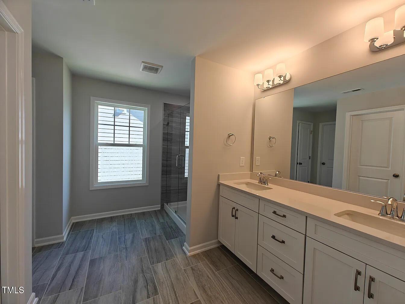 2409 Englemann Drive Apex, NC 27502 - Photo 13 of 25 a spacious bathroom with a double vanity sink a mirror a and a window