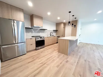 a view of kitchen with kitchen island granite countertop cabinets and wooden floor