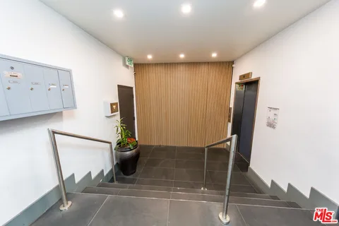 a view of empty room with wooden floor and kitchen