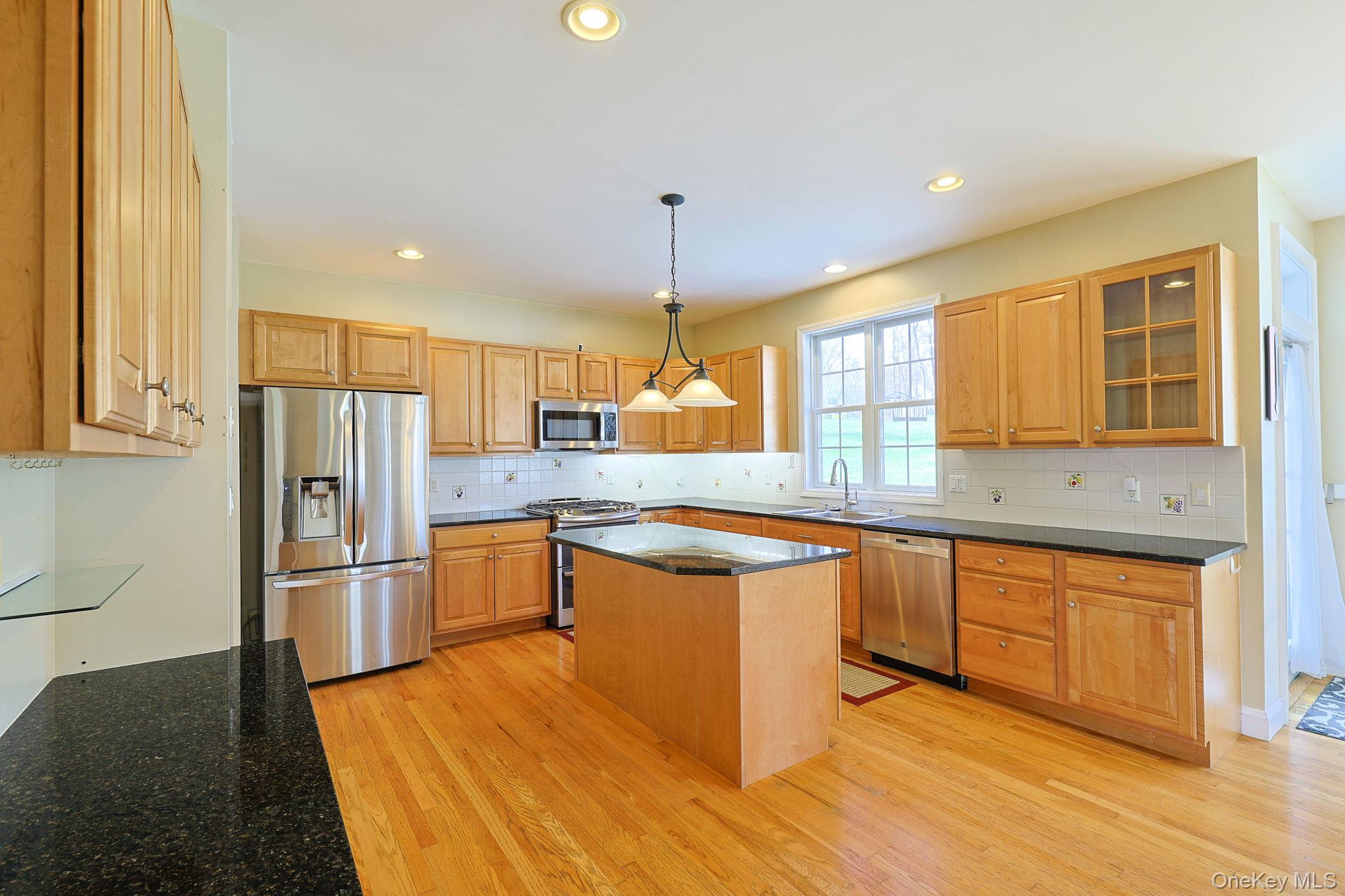 99 Country Club Road Hopewell Junction, NY 12533 - Photo 6 of 44 a kitchen with stainless steel appliances granite countertop a refrigerator a sink dishwasher a stove and a dining table with wooden floor