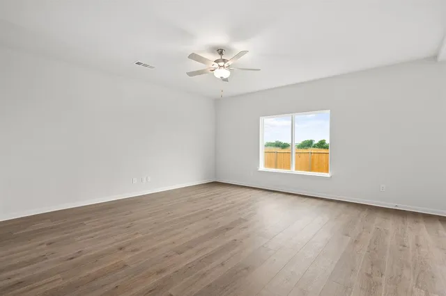 a view of an empty room with a window and wooden floor