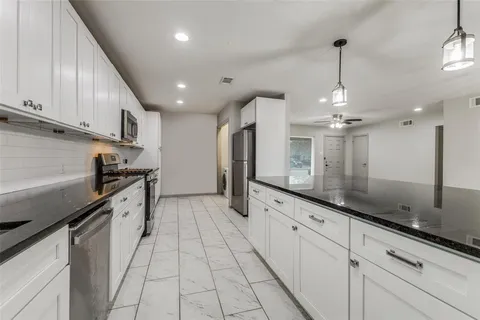 a large kitchen with stainless steel appliances granite countertop a stove a sink and a refrigerator