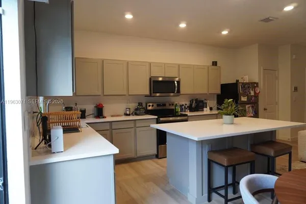 a kitchen with a sink a stove a refrigerator cabinets and a dining table