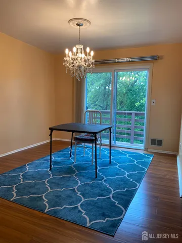 a view of a room with wooden floor a chandelier and windows