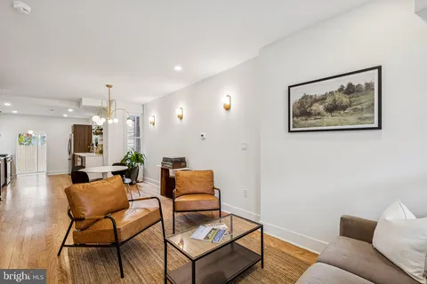 a living room with furniture and a dining table with wooden floor