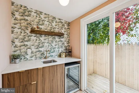 a view of a hallway with wooden floor a glass door with a kitchen space