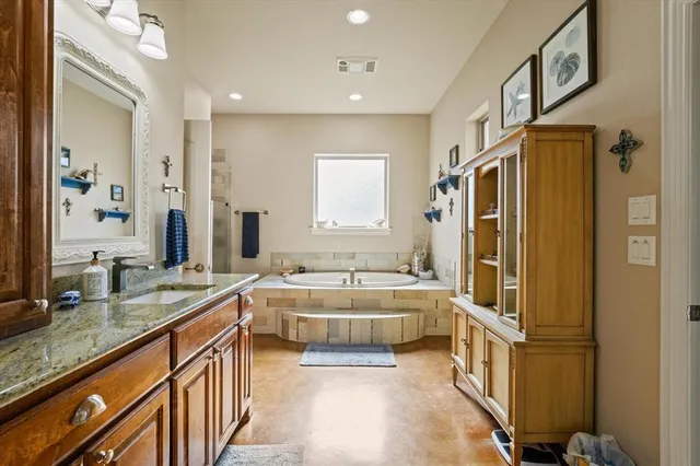 a bathroom with a granite countertop double vanity sink a mirror a bathtub and shower