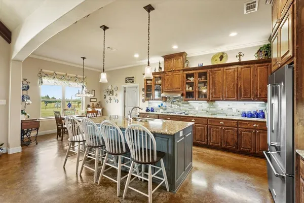 a kitchen with stainless steel appliances granite countertop a kitchen island a stove a sink a dining table and chairs with wooden floor