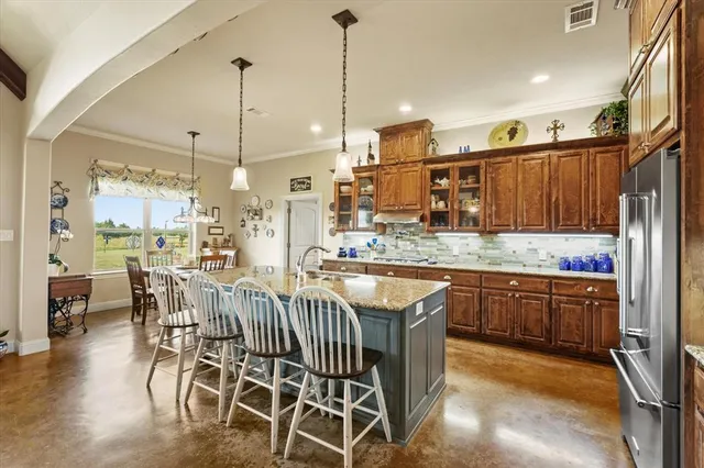 a kitchen with stainless steel appliances granite countertop a kitchen island a stove a sink a dining table and chairs with wooden floor