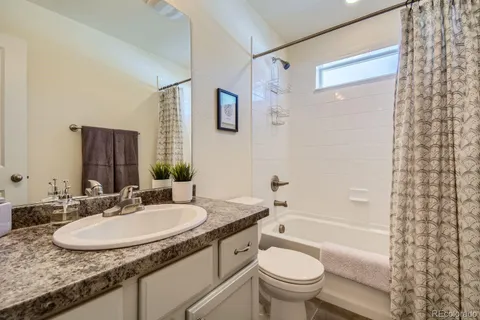 a bathroom with a granite countertop sink a toilet a mirror a bathtub and shower