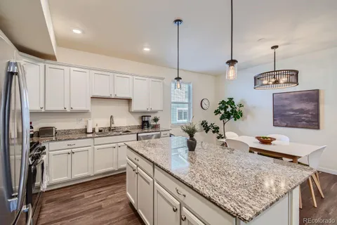 a kitchen with stainless steel appliances granite countertop a sink a stove and a wooden floor