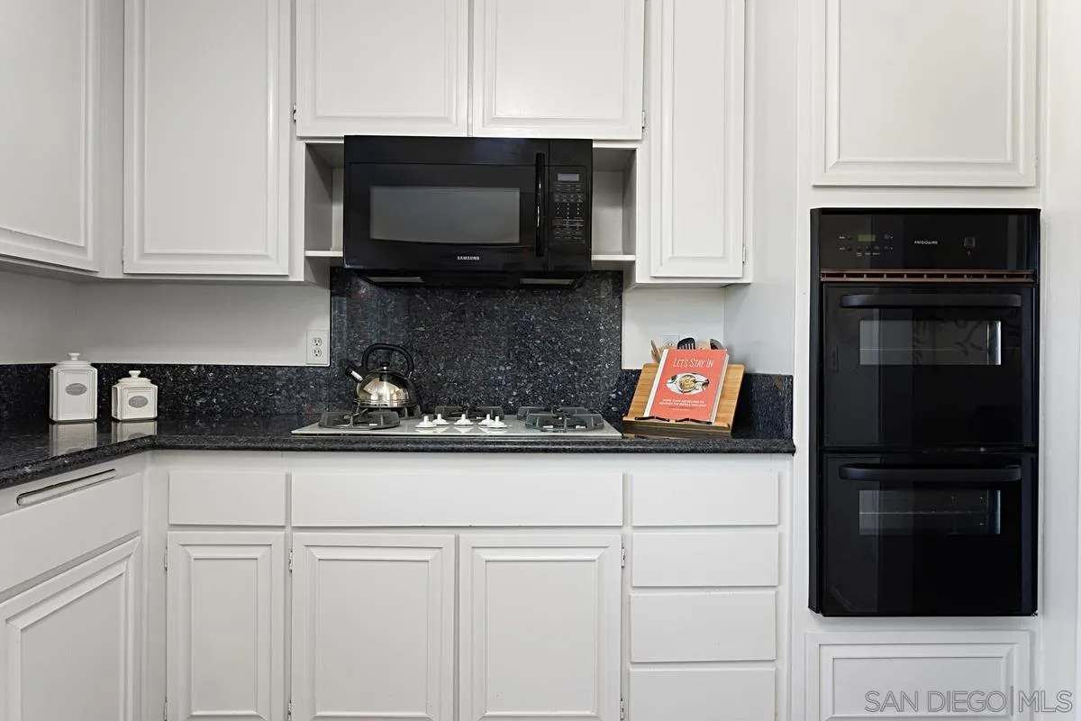 4520 Trieste Drive Carlsbad, CA 92010 - Photo 14 of 27 a kitchen with stainless steel appliances granite countertop a stove a microwave and cabinets