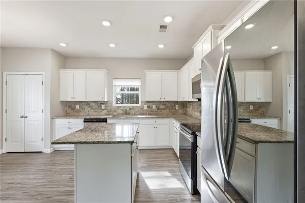 a kitchen with stainless steel appliances granite countertop a refrigerator and a sink