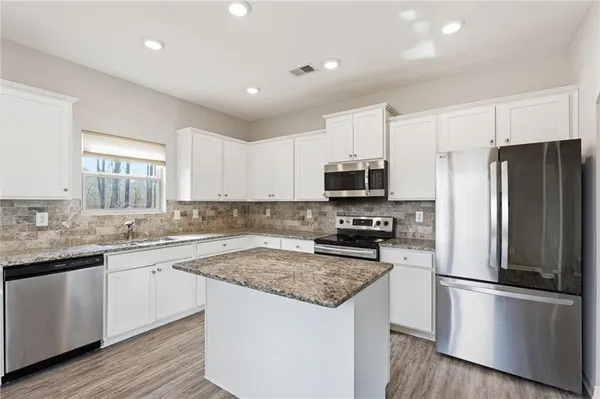 a kitchen with a sink a refrigerator a microwave and cabinets