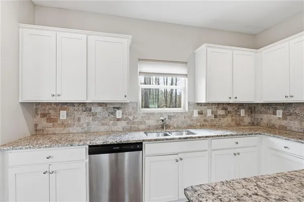 a kitchen with granite countertop white cabinets and white appliances