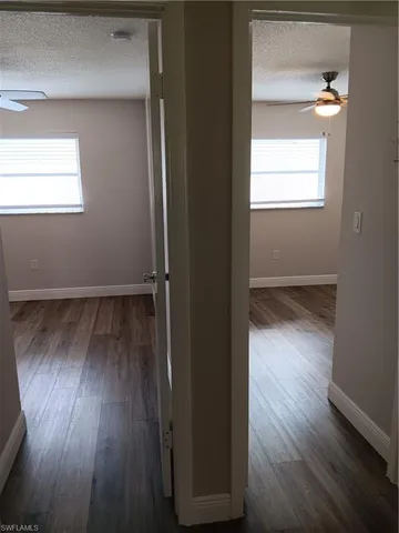 an empty room with wooden floor closet and windows