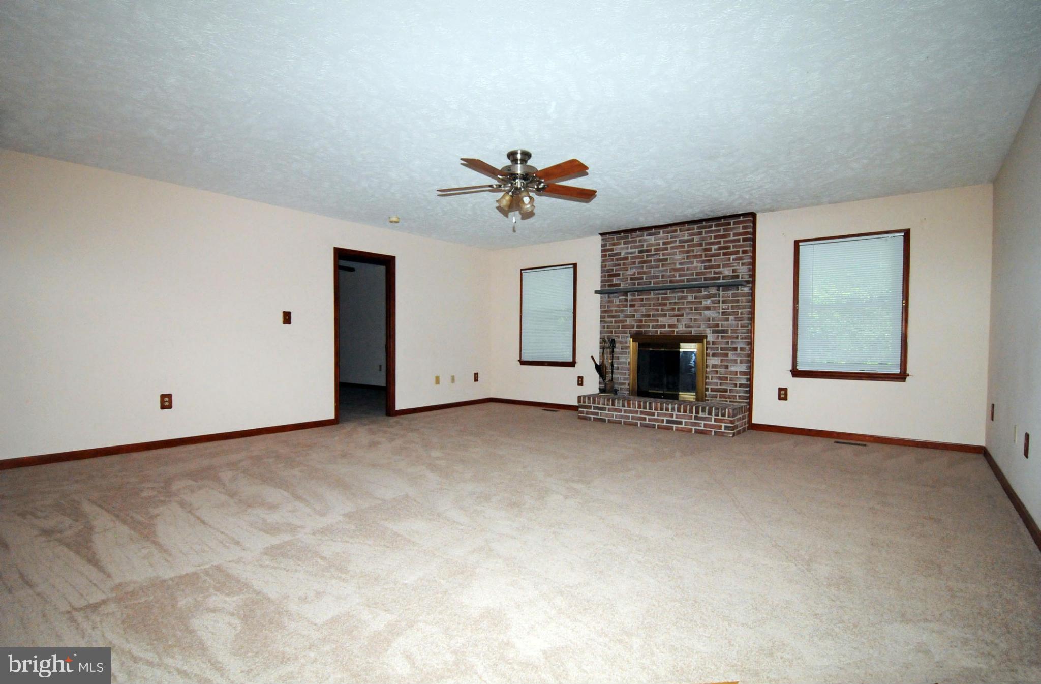 7881 Walnut Grove Road Severn, MD 21144 - Photo 3 of 21 an empty room with fireplace and a ceiling fan