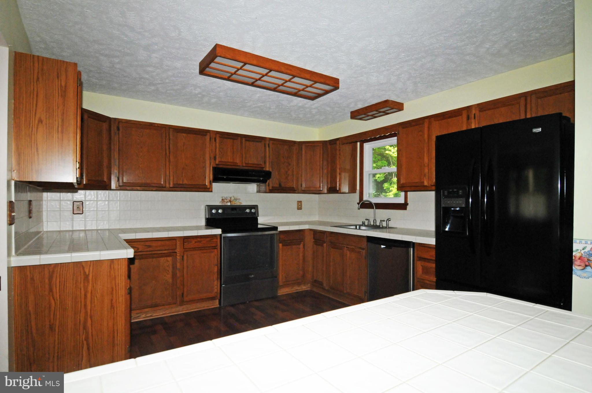 7881 Walnut Grove Road Severn, MD 21144 - Photo 7 of 21 a kitchen with stainless steel appliances kitchen island granite countertop a refrigerator a sink dishwasher and wooden cabinets