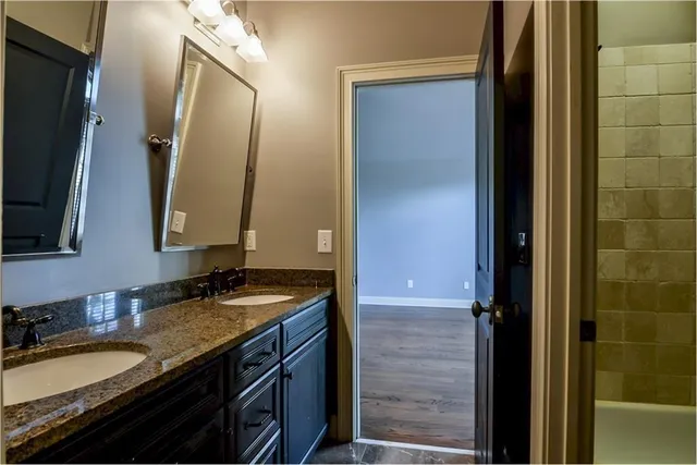 a bathroom with a granite countertop double vanity sink and a mirror