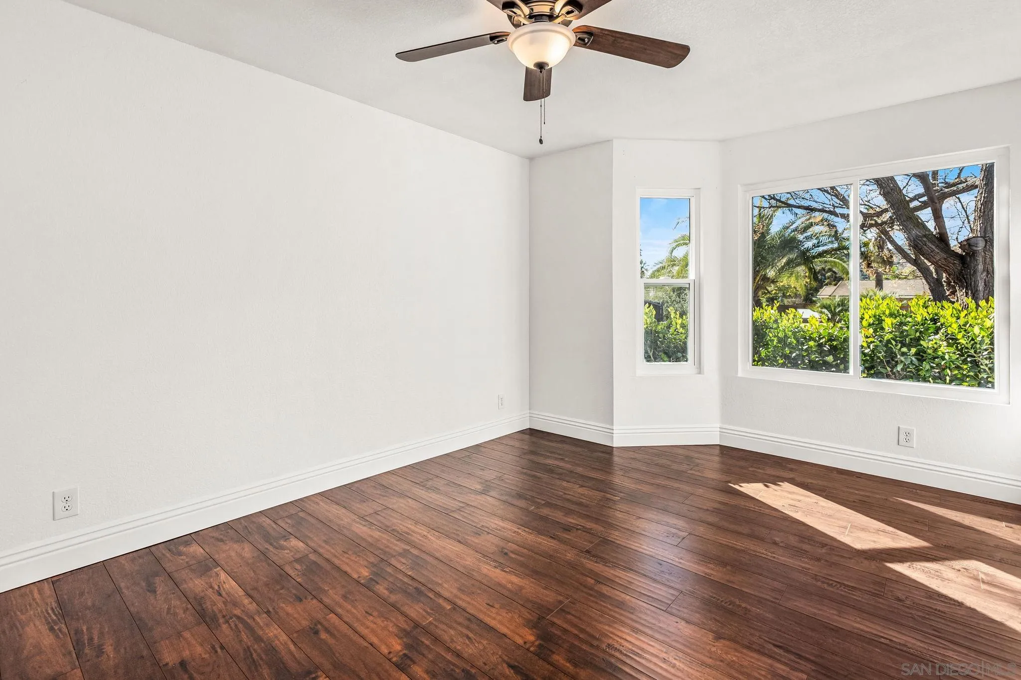 16319 Scarbery Road Ramona, CA 92065 - Photo 13 of 37 an empty room with wooden floor chandelier fan and windows