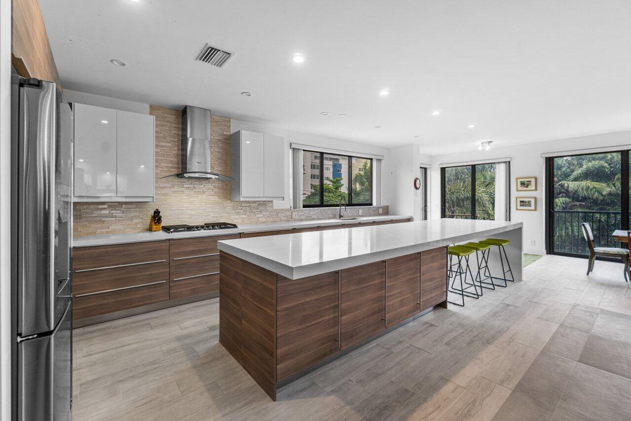 122 Andrews Avenue, Unit 2A Delray Beach, FL 33483 - Photo 9 of 39 a large kitchen with kitchen island a large counter top space a sink stainless steel appliances and cabinets