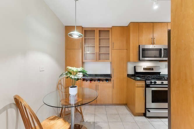 2 Hawthorne Place, Unit 16M Boston, MA 02114 - Photo 13 of 36 a kitchen with stainless steel appliances a stove a microwave a dining table and chairs