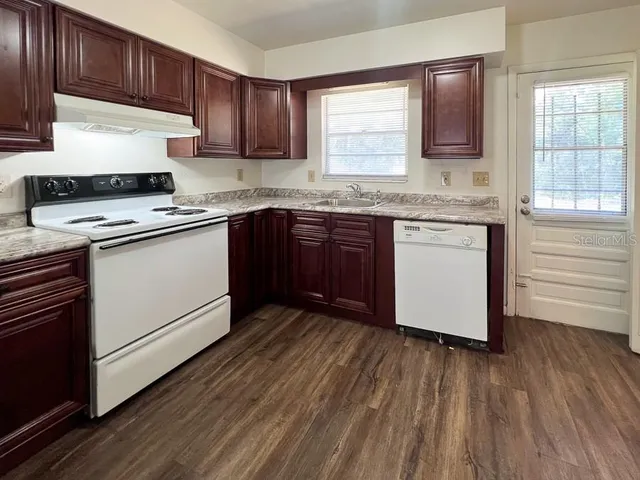 a kitchen with granite countertop wooden floors appliances cabinets and a center island
