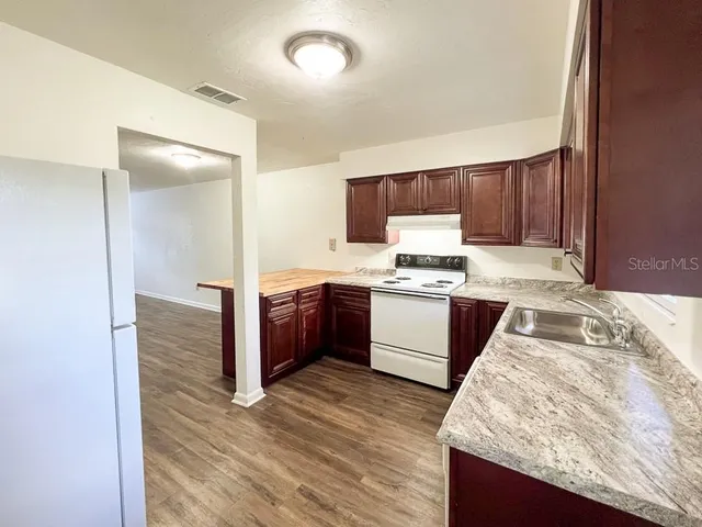 a kitchen with granite countertop wooden cabinets and white appliances