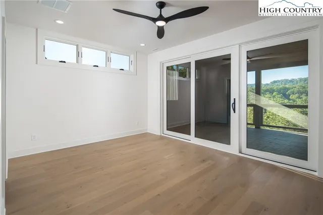 a view of an empty room with a window and kitchen view