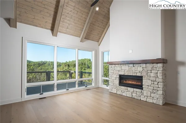a view of an empty room with wooden floor fireplace and a window
