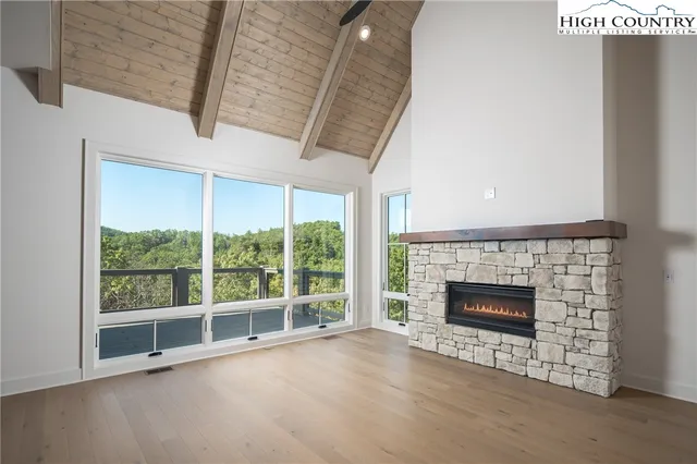 a view of an empty room with wooden floor fireplace and a window