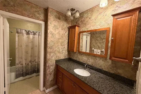 a bathroom with a granite countertop sink a mirror and shower