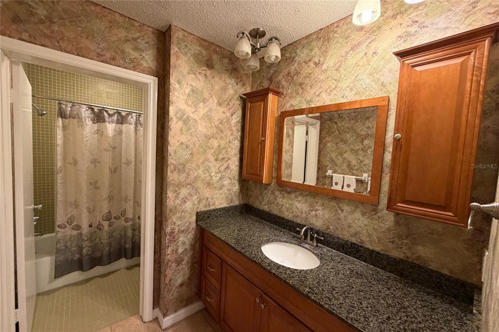 701 Poinsettia Road, Unit 340 Belleair, FL 33756 - Photo 11 of 24 a bathroom with a granite countertop sink a mirror and shower