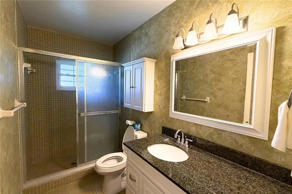 a bathroom with a granite countertop sink toilet and shower