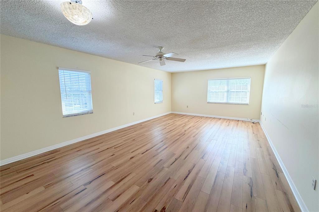 701 Poinsettia Road, Unit 340 Belleair, FL 33756 - Photo 5 of 24 an empty room with wooden floor chandelier fan and windows