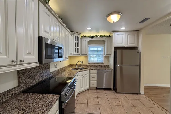 a kitchen with stainless steel appliances granite countertop a refrigerator a stove a sink and a microwave