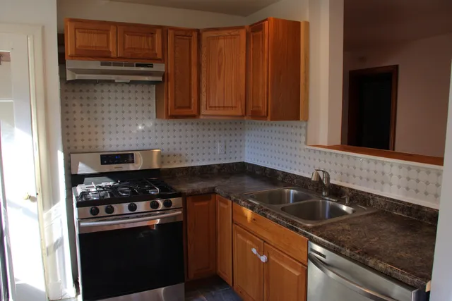 a kitchen with granite countertop a sink stove and cabinets