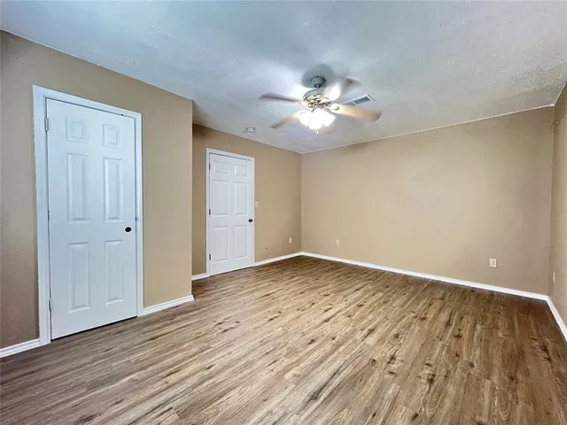 a view of empty room with wooden floor and ceiling fan