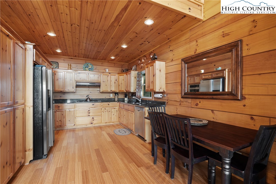 4923 Staghorn Road Purlear, NC 28665 - Photo 19 of 49 a kitchen with stainless steel appliances a refrigerator a stove a sink dishwasher a dining table and chairs with wooden floor