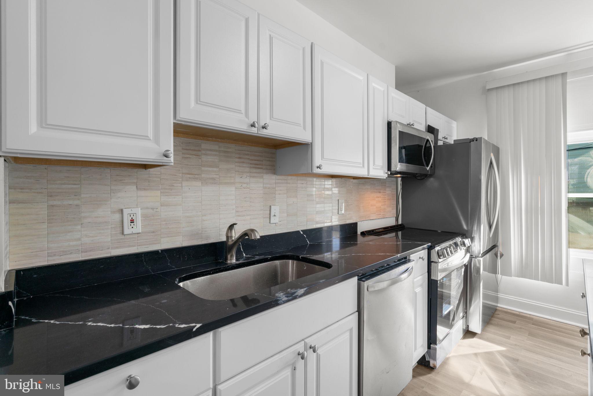 1731 Cliftview Avenue Baltimore, MD 21213 - Photo 10 of 33 a kitchen with granite countertop white cabinets sink and stainless steel appliances