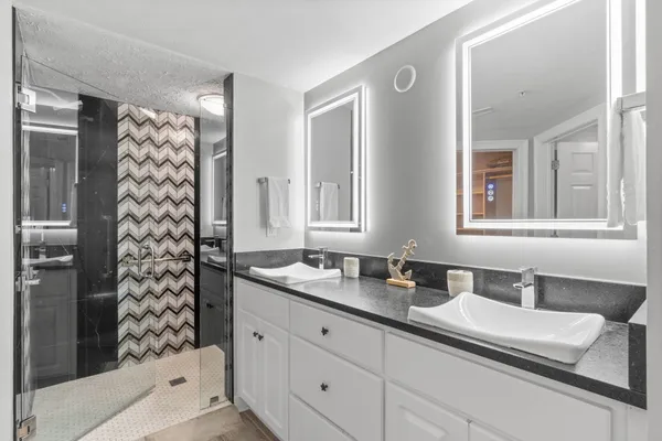 a bathroom with a sink a large mirror and a shower