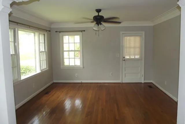 a view of an empty room with wooden floor and a window